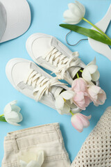 Wall Mural - Flowers in sneakers and light clothes on blue background, top view