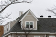 Dormer windows on the sloped shingle roof of a newly built family house on a winter day in Brighton, MA, USA