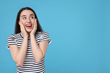 Wall Mural - Portrait of happy surprised woman on light blue background. Space for text