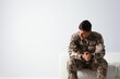Stressed military officer sitting on sofa against white background. Space for text