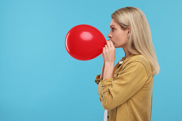 Poster - Woman blowing up balloon on light blue background. Space for text