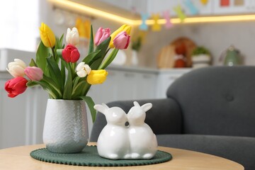 Sticker - Easter decorations. Bouquet of tulips and bunny figures on table indoors, closeup. Space for text