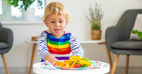 Wall Mural - Child eats vegetables at home. Selective focus.