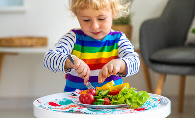 Wall Mural - Child eats vegetables at home. Selective focus.