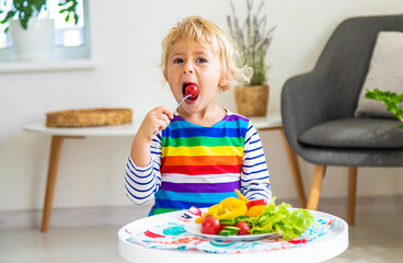 Wall Mural - Child eats vegetables at home. Selective focus.