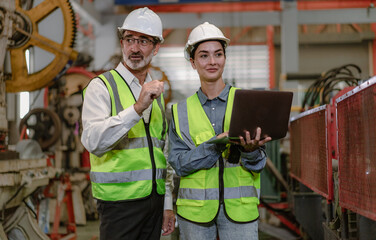 Wall Mural - Senior manager train female apprentice technician in metalwork production factory. Industrial engineer team standing working in manufacturing facility talking machinery maintenance in heavy steel job