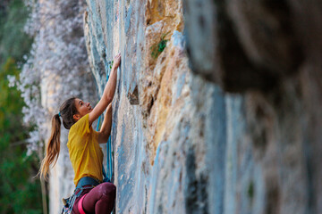 Wall Mural - Climber overcomes challenging climbing route. A girl climbs a rock. Woman engaged in extreme sport. .