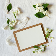 Sticker - envelope mockup and Blank greeting card made of jasmine flower branch and ribbon. Minimal floral frame invitation  . Flat lay, top view. Happy mother's day, women's day or birthday, wedding compositio