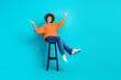 Full length portrait of overjoyed pretty person sit chair raise hands empty space isolated on turquoise color background