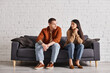multiethnic couple with relationship problem talking on couch in living room, divorce concept