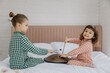 little girls play musical instruments in the parents' bedroom while sitting on the bed