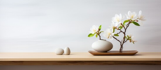 Wall Mural - A vintage wooden table shelf is adorned with a vase containing white flowers, accompanied by three rocks. The scene exudes a minimalist and zen aesthetic in a modern interior design setting.