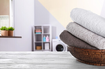 Canvas Print - Folded clean towels on grey wooden table in laundry room, space for text