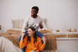 © Dmytro Hai - Positive multiethnic couple holding hands and coffee in bedroom