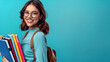 banner put on knowledge, smiling schoolgirl  holding textbooks on a blue background close-up with space for text
