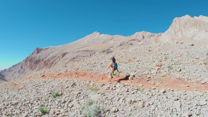 Wall Mural - adventure in the mountains. hiking with a backpack. a boy with a backpack walks along a path in the high mountains. Rock climbing and mountaineering concept.