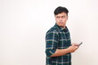 © ArvStd - Side view of Curious young asian man holding a cell phone while looking behind