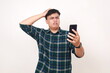 © ArvStd - Unhappy young asian man touching his head while holding a cell phone