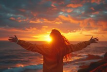 A carefree woman spreads her arms wide, embracing the dramatic sunset over a dynamic ocean landscape