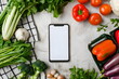 A blank mobile phone screen surrounded by vegetables on a kitchen counter