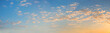 wide blue sky panorama with fleecy clouds and yellow shine, at dawn