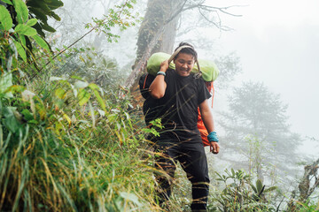Wall Mural - portrait of strong sherpa man working as porter carrying huge cargo with traditional method on foreh