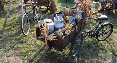 Wall Mural - aluminum milk cans brimming with fresh farm produce nestled in wooden cart with bike