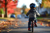 a little boy riding a bicycle with training wheels and a helmet