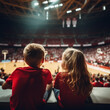 Two children watching a basketball game in the stadium.	
