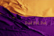 Purple and gold fabric with a gold brooch and the words 