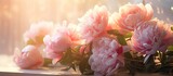 A collection of pink peonies is neatly arranged on a window sill, casting light and shadows against the blurred background.