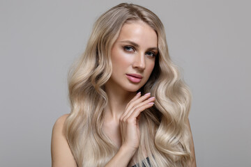 Wall Mural - Blonde girl with long wavy hair dyeing ombre touches her hair with her hand. Beautiful fashion woman