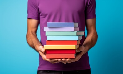 Wall Mural - man holding stacked up book against blue background