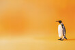 pingouin, oiseau marin noir et blanc avec le bec et la tête  à tâches orangées, aux pates palmées, vivant sur la banquise, sur un fond orange avec espace négatif pour texte copyspace