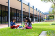 Two biracial girls are eating lunch on a school lawn