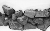 Fototapeta Na ścianę - close view of stone wall covered with snow in winter in black and white