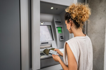 woman using credit card and withdrawing cash at the ATM