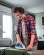 © Miljan Živković - one man ironing clothes at home hold iron household chores concept