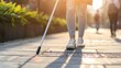 The lower half of a visually impaired person using a white cane to navigate a tiled walkway, highlighting independence