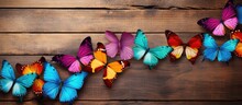 Multiple Decorative Butterflies Of Varying Colors Are Seen Perched On A Wooden Surface. The Vibrant Colors Of The Butterflies Contrast Beautifully With The Natural Wood Texture.