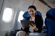 © chartchai - Young Asian executives are first class. Multitask with digital tablets, laptops and smartphones. Travel in style.