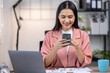 © David - Portrait of happy young asian woman accountant working documents on laptop and  phone desk using calculator for calculate finance report in home office