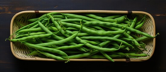 Wall Mural - A basket filled with green beans sits atop a table. The vibrant green beans are neatly arranged in the basket, creating a visually appealing display.