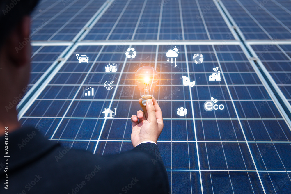 Businessman's hand holds a light bulb on a solar panel future energy ...