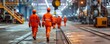 Back view of factory workers in hard hats and orange uniforms are walking in a factory