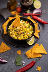 Canvas Print - Freshly made mango salsa in a black ceramic bowl and nacho chips