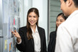 © Bavorndej - Dynamic businesswoman actively engages with her colleagues, presenting and explaining concepts on a storyboard in a corporate setting.