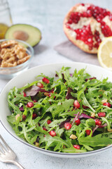 Wall Mural - A plate with green rocket salad with pomegranate and avocado