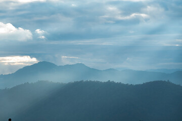 Wall Mural - Sun rays filter through the clouds in hills of the valley illuminated by the sun's rays filtering through the clouds