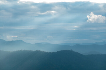 Wall Mural - Sun rays filter through the clouds in hills of the valley illuminated by the sun's rays filtering through the clouds